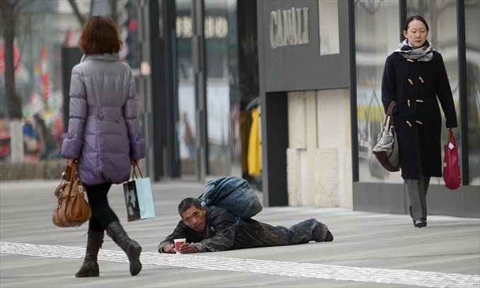 A seemingly disabled beggar prostrates himself in Chengdu, Sichuan Province on December 26, 2012. Reporters followed him for days and found he stood up, changed into clean clothes and left in a taxi every day. Photo: CFP