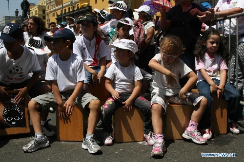 Children attend the VI Peruvian Cajon International Festival at Plaza de Armas in Lima City, capital of Peru, on April 13, 2013. Over a thousand people gathered here on Saturday to play their Cajones, breaking a Guinness World Record for the world's largest cajon ensemble. (Xinhua/Luis Camacho)