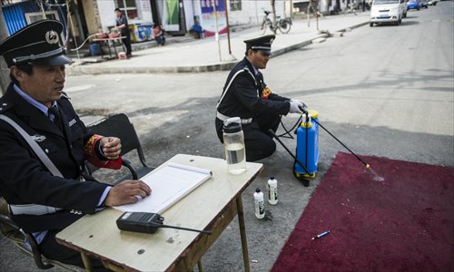 A security guard disinfects a rug at the entrance to Gucheng village in Shunyi district, Beijing, where the city’s first confirmed bird flu case was reported on Saturday. Photo: Li Hao/GT