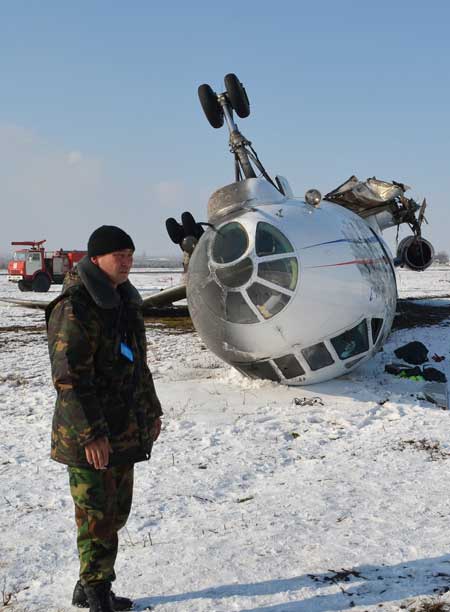 A security guard stands near an overturned Tupolev Tu-34 passenger jet at the airfield outside the southern Kyrgyz city of Osh Thursday. The packed jet flipped over and caught fire on landing in Osh on Wednesday. Photo: AFP