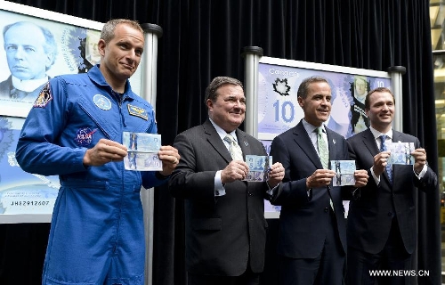 (L-R) Canadian Space Agency astronaut David Saint-Jacques, Canada's Finance Minister Jim Flaherty, Bank of Canada Governor Mark Carney and Chair of the board at VIA Rail Canada Paul G. Smith hold the newly unveiled 5-dollar and 10-dollar polymer bank notes at the Bank of Canada in Ottawa, Canada, April 30, 2013. Canada' s central bank on Tuesday added the last two banknotes to its polymer note series, which started in 2011 in its latest efforts to fight against counterfeit currency. (Xinhua/James Park) 