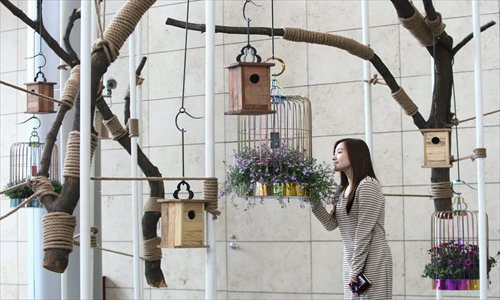A visitor examines a bird cage decorated with flowers at the Shanghai Environmental Art Fair Tuesday. The spring fair at the Shanghai World Financial Center aims to help people recognize the natural beauty of the world. Photo: CFP