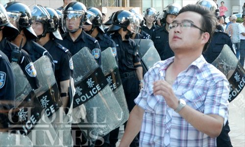 A local resident in Qidong, Jiangsu Province, passed by the police force of Qidong during a demonstration there against the construction of an industrial waste pipeline of the Japan-based Oji Paper Group on July 28, 2012. Photo: Cai Xianmin/GT