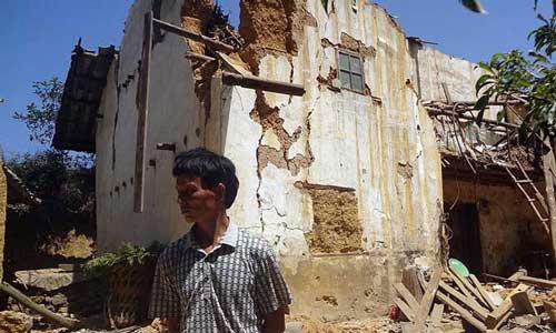 A man stands in front of a damaged house in Xinlong Village of Weining County, southwest China's Guizhou Province, Sept. 7, 2012.
