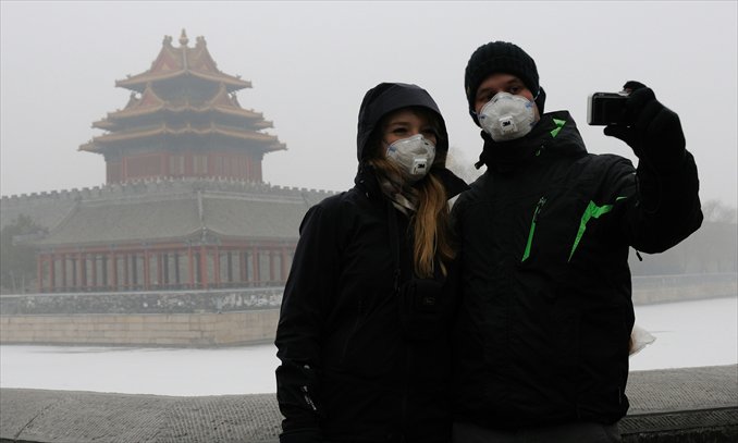 Foreign tourists take pictures of themselves near the Forbidden City in Beijing on January 30. The city suffered heavy air pollution this winter. Photo: CFP