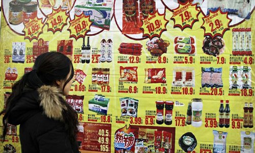 A consumer looks at discount information in a supermarket in Handan, north China's Hebei Province, December 9, 2012. China's consumer price index (CPI), a main gauge of inflation, grew 2 percent year on year in November, the National Bureau of Statistics announced Sunday. The inflation rate increased from a 33-month low of 1.7 percent in October as food prices increased. Photo: Xinhua