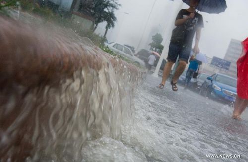 People wade through a flooded street in Tianjin, North China, July 26, 2012. Heavy rainfall hit the municipality from Wednesday afternoon to Thursday. Photo: Xinhua

