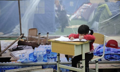 A primary school student does her homework at a temporary settlement at the Hainan Middle School in Baoxing on April 24, 2013. Photo: Li Hao/GT