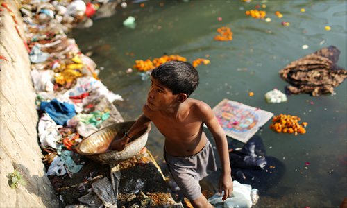 An Indian scavenger looks for recyclable items near a Hindu bathing site in the polluted Yamuna river in New Delhi on Sunday. India's Supreme Court said on Saturday that all parameters for water quality of river Yamuna indicate that it resembles a drain and urged authorities to make it pollution-free. Photo: 