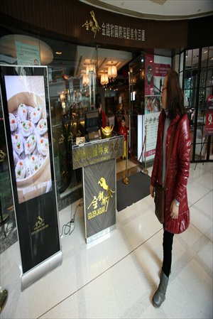 A woman passes by a Golden Jaguar restaurant, a seafood buffet chain, in Shanghai Thursday. China Central Television recently reported that some restaurants were using 