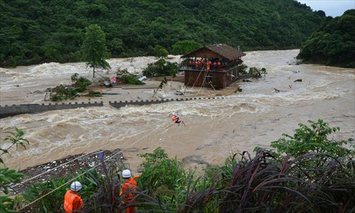 Firefighters cross the river with ropes to rescue people trapped by heavy rains that flooded the Chonghuanggou tourist resort in Fangchenggang city, Guangxi Zhuang Autonomous Region Monday. The city was hit by a torrential downpour Monday which lead to a severe flood in the mountainous Chonghuanggou area. Some 14 people were trapped and successfully rescued by Monday evening. Photo: IC