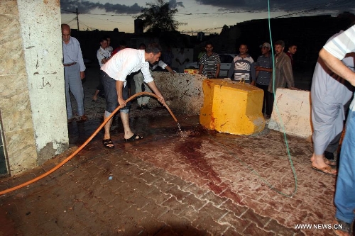 People clean the blast site at a Shiite mosque in Kirkuk, northern Iraq, May 16, 2013. At least 12 people were killed and 25 others injured as a suicide bomber blew himself up at a Shiite mosque in northern Iraq's Kirkuk on Thursday, local police sources said. (Xinhua/Dena Assad) 
