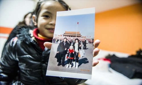 Zhong Tingting, 7, shows a photo of her, surrogate father Zhong Zhengchi and his older daughter taken at Tiananmen Square Saturday. Photo: Li Hao/GT