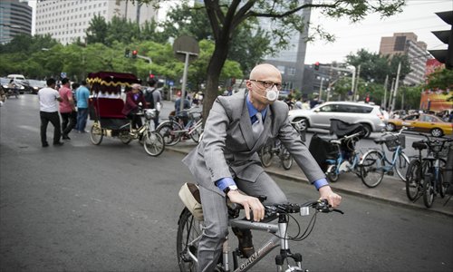 An expat wearing a mask cycles through Sanlitun in Chaoyang district earlier this month
