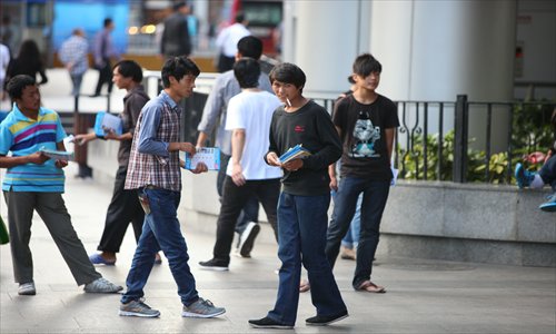 Touts for unlicensed travel companies hand out leaflets around the Lujiazui subway hoping to lure tourists. Photo: Cai Xianmin/GT