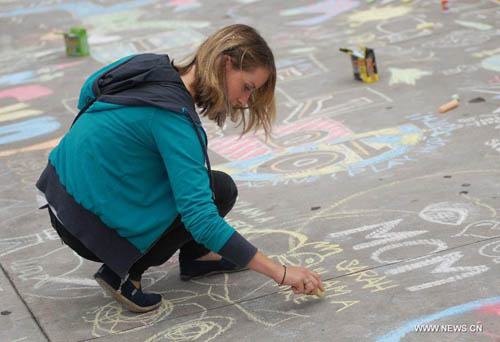 A woman chalk-draws on the pavement during first Chalkupy Vancouver event in Vancouver, Canada, on September 22, 2012. People from all walks of life descend on Robson Street in downtown Vancouver at noon to create beautiful sidewalk chalk art together. Photo: Xinhua