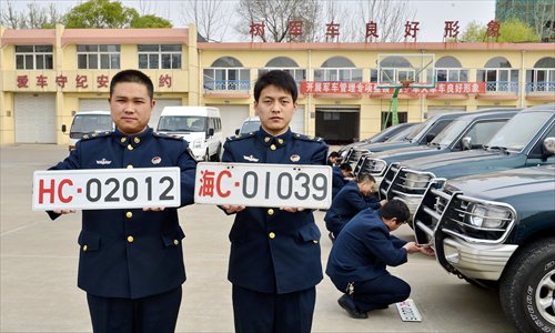Two Chinese naval officers present two sets of military vehicle plates in Qinhuangdao, Hebei Province on Sunday. The new plate on the left contains high-tech features to prevent forgeries. The old plate's use of the Chinese character