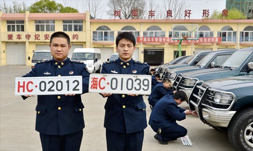 Two Chinese naval officers present two sets of military vehicle plates in Qinhuangdao, Hebei Province on Sunday. The new plate on the left contains high-tech features to prevent forgeries. The old plate's use of the Chinese character 