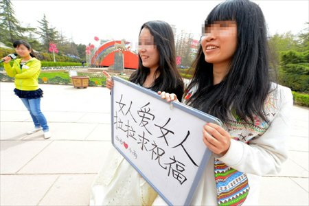 Lesbian lovers Xixi and Xiaoyu held a wedding ceremony in a park in Lanzhou, northwest China's Gansu province on April 15, 2013. Wearing wedding dress and holding a sign reading 