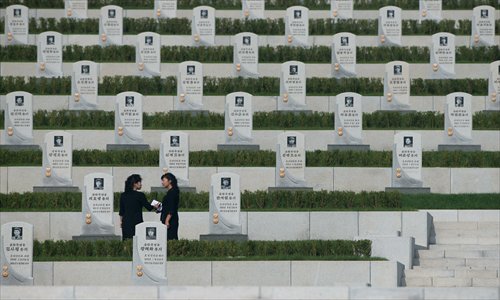 Two North Korean women stand between tombstones during the inauguration of a Korean War military cemetery in the capital Pyongyang on Thursday. Selected remains of North Korean soldiers deemed to be heroes of the war were relocated from around the country to the new site. Photo: AFP