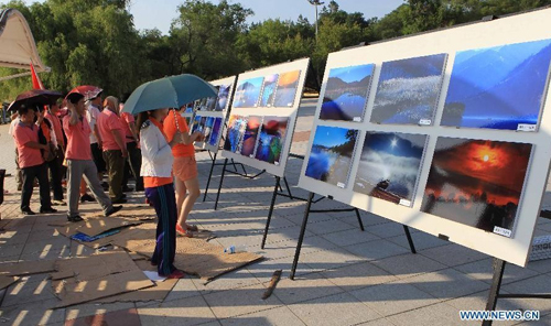 Tourists view photos about the Jingpo Lake at the Jingpo Lake scenic area in Mudanjiang, northeast China's Heilongjiang Province, July 7, 2012. About 30 percent more tourists have visited the Jingpo Lake scenic area this year than the same period last year, following a series of promotions. Photo: Xinhua