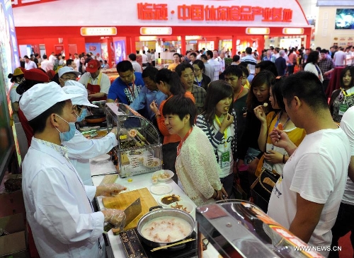 People tastes food provided by manufacturers during the 11th China (Luohe) Food Fair in Luohe City, central China's Henan Province, May 16, 2013. The five-day food fair, with an exhibition area of 50,000 square meters and attracting more than 1,500 enterprises from 17 countries and regions, opened here on Thursday. (Xinhua/Li Bo)