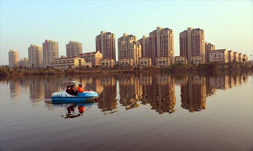 People go boating Saturday on a lake in Poyang county, East China's Jiangxi Province, with a new housing project in the background. Photo: CFP