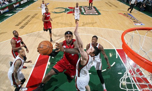 LeBron James (in red) of the Miami Heat drives to the basket against Ersan Ilyasova of the Milwaukee Bucks in game three of the Eastern Conference quarterfinals during the 2013 NBA playoffs on Thursday at the BMO Harris Bradley Center in Milwaukee, Wisconsin. Photo: AFP