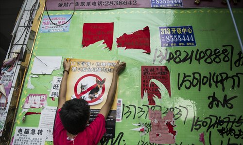 An animal rights advocate puts up a poster that calls for people not to eat dogs and cats. Photo: Li Hao/GT