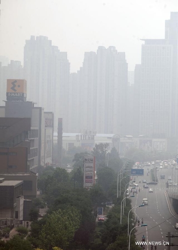 Fog-shrouded buildings are pictured in Tianjin, north China, June 18, 2013. Local meteorological authorities issued a yellow fog alert on Tuesday morning. (Xinhua/Liu Dongyue)