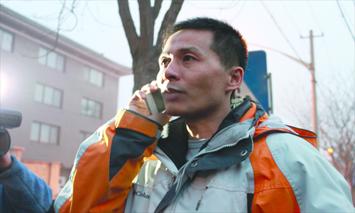 Zhu Ruifeng picks up a phone for an interview with a foreign reporter outside the Dewai police station in Beijing on January 28, after walking out of a seven-hour negotiation session with Chongqing police. Photo: Chang Meng/GT