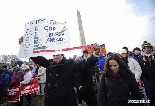 People hold signs against gun violence in front of the Washington Monument during a march in Washington D.C., capital of the United States, Jan. 26, 2013. Thousands of people, including family members of victims and survivors of shootings at Virginia Tech University, Sandy Hook elementary school and others, took part in a march for stricter gun control laws here on Saturday. (Xinhua/Zhang Jun) 