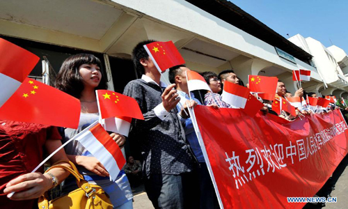 People wave flags to welcome the arrival of the Chinese Navy training vessel 