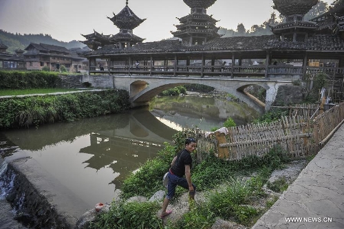 A woman walks past a brook in Dimen Dong minority village in Liping County of southwest China's Guizhou Province, June 20, 2013. Dimen is a Dong minority village with about 2,500 villagers. It is protected properly and all the villagers could enjoy their peaceful and quiet rural life as they did in the past over 700 years. (Xinhua/Ou Dongqu)