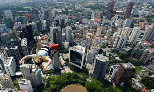 Basejumper Anton Chervyakov from Russia leaps from the top of the 421-meter Kuala Lumpur Tower during the International Tower Jump in Kuala Lumpur, Malaysia on Thursday.  Some 95 professional basejumpers from 18 countries and regions are taking part in the annual event. Photo: AFP