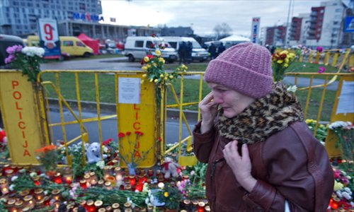 A woman cries as she walks by flowers and candles surrounding the Maxima supermarket in Riga on Sunday, three days after the roof of the building caved in on shoppers, which killed at least 54 people. The small Baltic state began three days of grieving over the incident, which is Europe's third worst roof disaster in 30 years. Photo: AFP