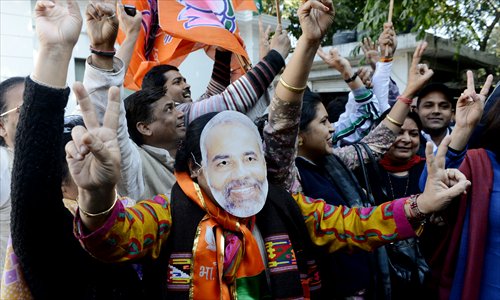 An Indian supporter of the Bhartiya Janta Party (BJP) wearing a mask of Chief minister of Gujarat, Narendra Modi, celebrate the assembly election results being declared in New Delhi on Thursday. Modi is heading for a landslide election win in Gujarat on, firming up his chances of being nominated by the BJP for running for prime minister in 2014. Photo: AFP 