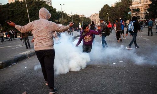 An Egyptian protester throws a teargas back during clashes between anti-government protesters and riot police near Tahrir square in Cairo, March 9, 2013. Two protesters were killed during the clashes. (Xinhua/Amru Salahuddien)
