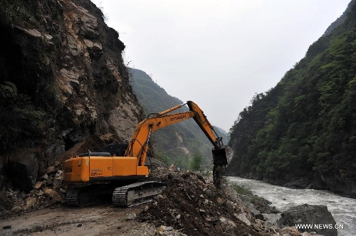 An excavator works to clear the way liking the quake-hit Lushan County to Lingguan Town of Baoxing County in southwest China's Sichuan Province, April 21, 2013. After two days of work, traffic was preliminarily restored on Sunday on a quake-damaged section of the S210 highway that connects the isolated Baoxing County with neighboring Lushan County, the epicenter of the quake. More rescue and relief supplies have been transported to the county through the highway. (Xinhua/Liu Chan) 