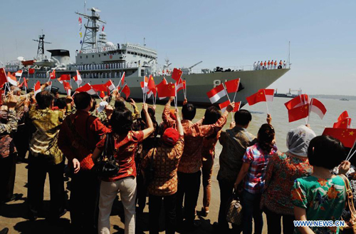 People wave flags to welcome the arrival of the Chinese Navy training vessel 