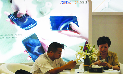 Two Alipay users pay their bills via mobile phones at an Alipay exhibition booth in Shanghai on September 16, 2013. Photo: IC