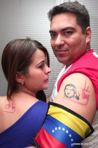 A man shows his tattoo with the image and sign of late Venezuelan President Hugo Chavez in the city of Caracas, capital of Venezuela, on March 15, 2013. The body of late Venezuelan President Hugo Chavez was carried from the Military Academy to the Mountain Barracks, in the city of Caracas, on Friday. Hundreds of thousands of Venezuelans Friday marched alongside the casket of their late President Hugo Chavez, as his remains were taken to the mountaintop barracks he once called home and today houses the Historic Military Museum. (Xinhua/AVN)