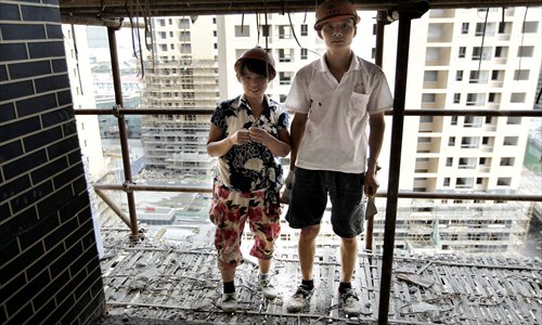With their tools in hand, a couple pose for the Global Times photographer in front of a nearly-finished apartment building. Photo: Yang Hui/GT