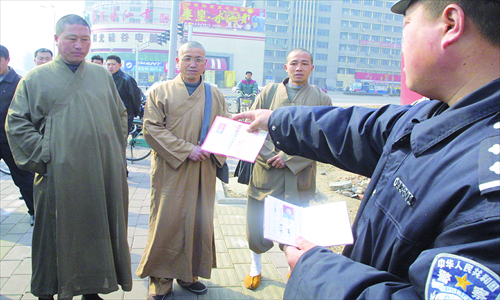 A police officer checks the ID cards of four imposter monks.