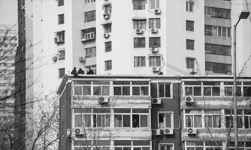 A male petitioner (left) in his 60s sits on a roof threatening to commit suicide by jumping from a residential building near Dawanglu Subway Station at 2:30 pm Monday. The man was finally persuaded to come down and was taken away by local police. Photo: Li Hao/GT