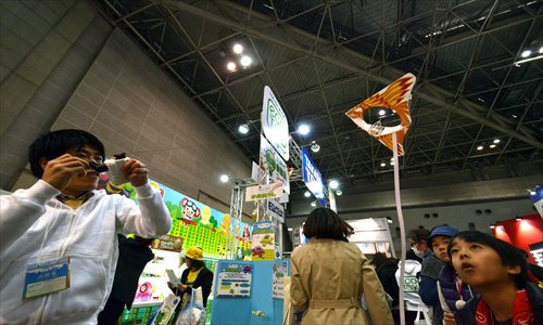 An employee (L) of Japan's toy giant Tomy demonstrates an indoor 
