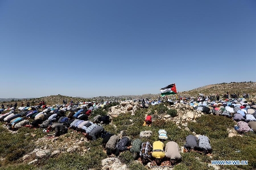 Palestinian protesters pray during a protest against settlement's expansion and settlers attack in the west bank village of Dir Jrer near Ramallah on April 26, 2013. Six protesters were injured during clashes between Palestinians and Israeli soldiers. (Xinhua/Fadi Arouri) 