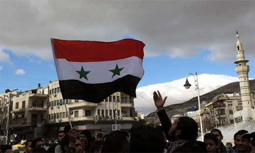 Youngsters wave flags during demonstration in front of the state bank in Damascus, Syria, Feb. 12, 2013. Photo: Xinhua