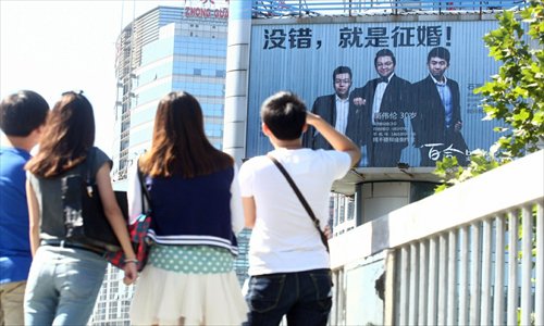 Pedestrians look at a billboard in a public square in Zhongguancun, Beijing, showing lonely hearts ads featuring three male office workers. Zhang Yang, one of the three, who works with an e-commerce company, said they are all in their 30s and they each paid 50,000 yuan ($7,871) for the month-long ad exposure. Photo: CFP