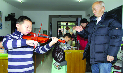 Wu Huoran, 75, an empty nester from Chongqing who rose to fame for seeking single women to live with him rent-free, teaches a boy violin during a break in a calligraphy class on November 18. Photo: CFP